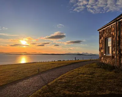 a building on the shore of a body of water at Blaeberry Cottage in Killean