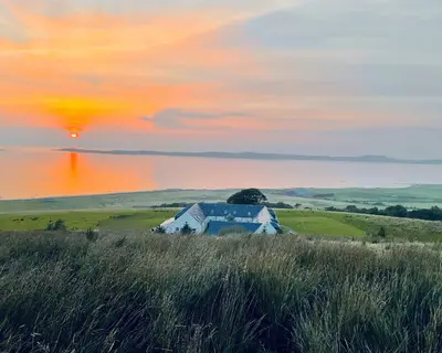 a barn in a field with a sunset in the background at Primrose Cottage in Killean