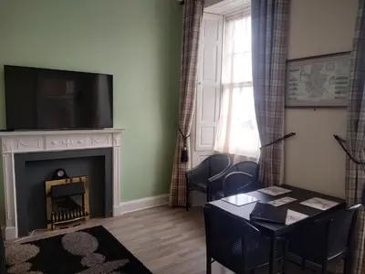 a living room with a fireplace with a tv and a table at Glasgow city Charlotte service Aparments in Glasgow
