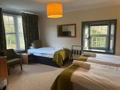 a room with two beds and a chair and windows at Rowardennan Hotel in Rowardennan