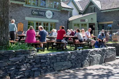 a group of people sitting at picnic tables in front of a building at Oak Tree Inn in Balmaha