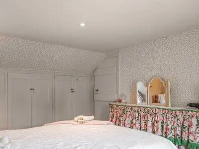 a bedroom with a white bed with a floral curtain at Ivy Cottage in Crieff