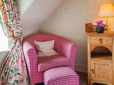 a red chair with a pillow in a room at Ivy Cottage in Crieff