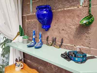 a shelf with a blue vase on a brick wall at Ivy Cottage in Crieff