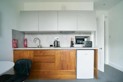 a kitchen with white cabinets and a sink at Meadow Apartment in Dumbarton