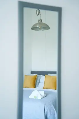 a bedroom with a bed with yellow pillows and a mirror at Meadow Apartment in Dumbarton