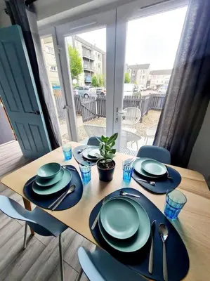 a wooden table with plates and utensils on it at Spacious 5bed house, FREE parking, NO PARTY ! in Glasgow