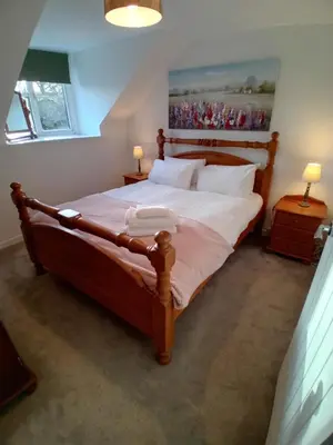a bedroom with a large wooden bed with white sheets at Killean Farmhouse Cottages in Auchnangoul