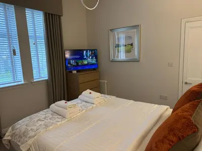a bedroom with a bed and a tv and windows at Luxury 2 Bedroom Cottage in West Calder