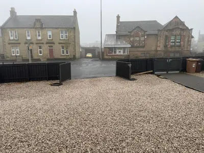 a gravel parking lot with houses and a fence at Luxury 2 Bedroom Cottage in West Calder