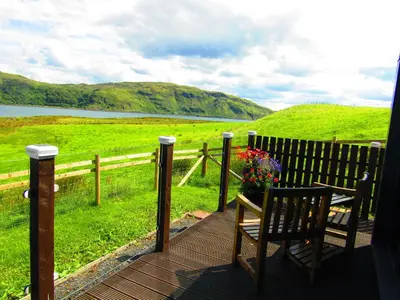 a wooden deck with a bench and flowers on it at Balvicar Beag in Oban