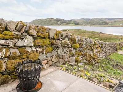 a stone wall with a trash can next to it at Balvicar Beag in Oban