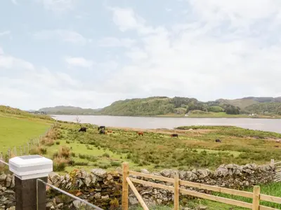 a view of a lake from a farm with a fence at Balvicar Beag in Oban