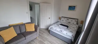 a living room with a couch and a bed at Cove Bay 1 Bed Flat in Largs