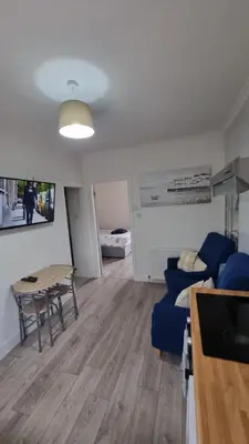 a living room with a table and a blue couch at Cove Bay 1 Bed Flat in Largs
