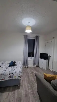 a bedroom with a bed and a couch and a television at Cove Bay 1 Bed Flat in Largs