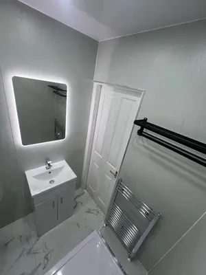 a white bathroom with a sink and a mirror at Cove Bay 1 Bed Flat in Largs
