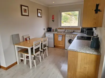 a kitchen with a table and a sink and a stove at Kings Reach - Crinan Cottage in Lochgilphead