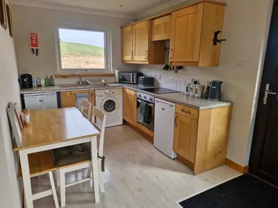 a kitchen with wooden cabinets and a sink and a table at Kings Reach - Crinan Cottage in Lochgilphead