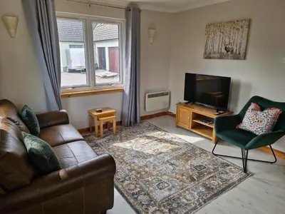 a living room with a couch and a television at Kings Reach - Crinan Cottage in Lochgilphead