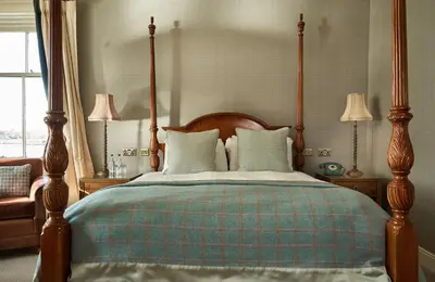 a bedroom with a bed with a wooden frame and two lamps at Oban Bay Hotel in Oban