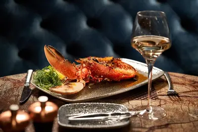 a plate of food and a glass of wine on a table at Oban Bay Hotel in Oban