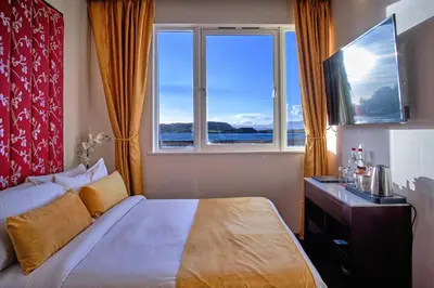 a bedroom with a bed and a large window at Muthu Oban Regent Hotel in Oban
