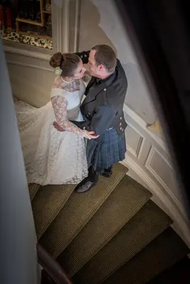 a bride and groom kissing on the stairs at The Royal Hotel in Oban