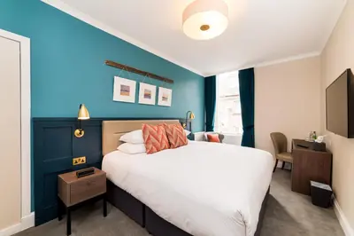 a bedroom with a large bed and a blue wall at The Perle Oban Hotel & Spa in Oban