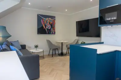 a living room with a couch and a painting on the wall at Combie Lane Apartment in Oban