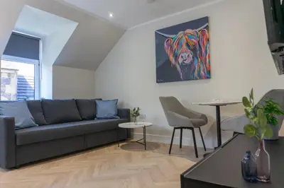 a living room with a couch and a painting on the wall at Combie Lane Apartment in Oban