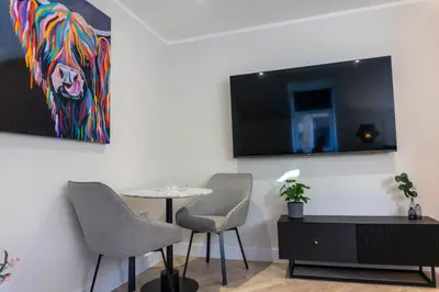 a room with a table and two chairs and a painting at Combie Lane Apartment in Oban