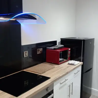 a kitchen with a black refrigerator and a counter top at J & S Apartments in Ayr