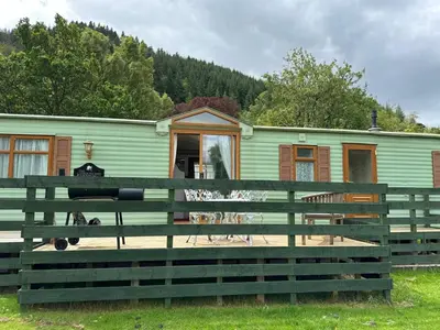 a green house with a fence in front of it at The Lambourne 71 in Dunoon