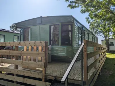 a green trailer sitting on a wooden deck at 55 Glenfinart Caravan Park in Dunoon