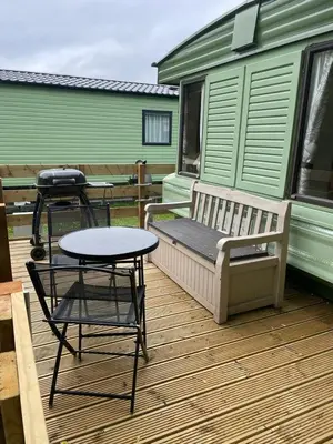a deck with a bench and a table and a table and chairs at 55 Glenfinart Caravan Park in Dunoon