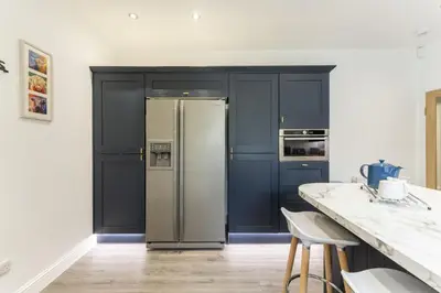a kitchen with blue cabinets and a stainless steel refrigerator at The Lindsay House in Stirling