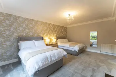 a bedroom with two beds and a chandelier at The Lindsay House in Stirling