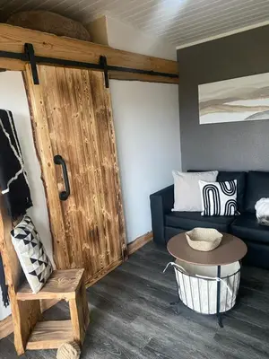 a living room with a blue couch and a wooden door at Devon River Glamping Pods in Alloa