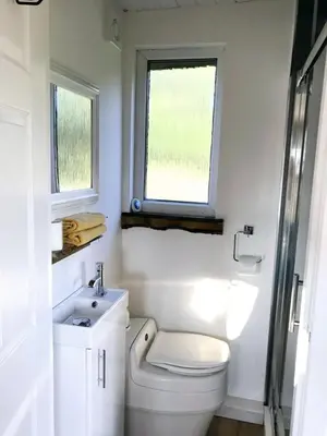 a bathroom with a toilet and a sink and a window at Devon River Glamping Pods in Alloa