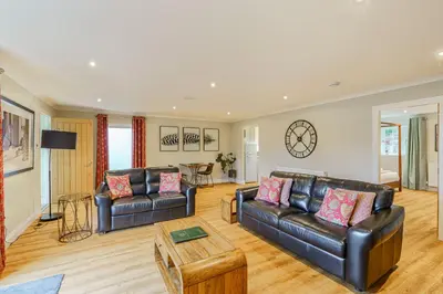 a living room with two leather couches and a table at Peregrine Cottage with Hot Tub in Newton Stewart