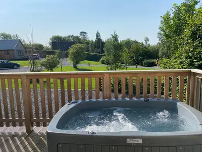 a hot tub on a deck with a wooden fence at Peregrine Cottage with Hot Tub in Newton Stewart