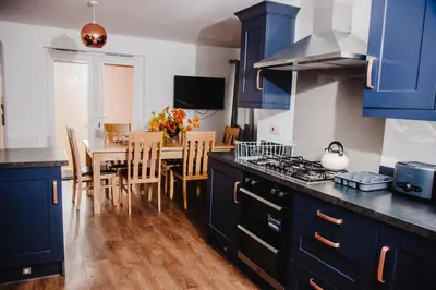 a kitchen with blue cabinets and a table with chairs at Beautiful 5 Bedroom House in Glasgow in Cambuslang