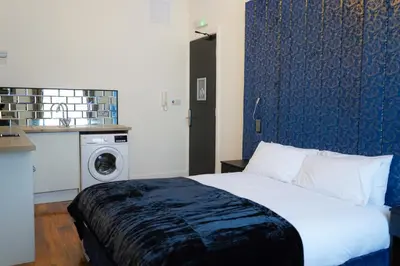 a bedroom with a bed and a washing machine at Novana Aparthotel in Glasgow