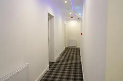 a hallway with white walls and a checkered floor at Novana Aparthotel in Glasgow