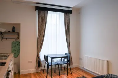 a kitchen with a table and two chairs in front of a window at Novana Aparthotel in Glasgow