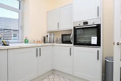 a white kitchen with white cabinets and a microwave at Burnside in Tighnabruaich