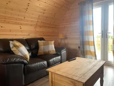 a living room with a leather couch and a coffee table at Pond View Pod 2 with Private Hot Tub - Fife - Loch Leven - Lomond Hills in Kelty