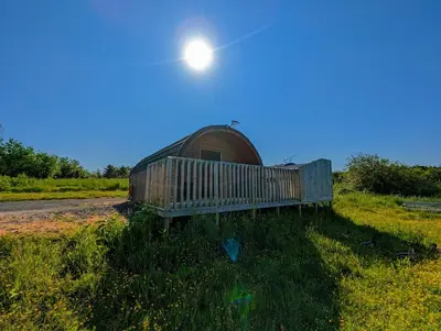 a bench in a field with the sun in the sky at Pond View Pod 2 with Private Hot Tub - Fife - Loch Leven - Lomond Hills in Kelty