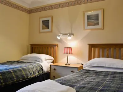 a bedroom with two beds and a lamp on a night stand at Duart in Onich